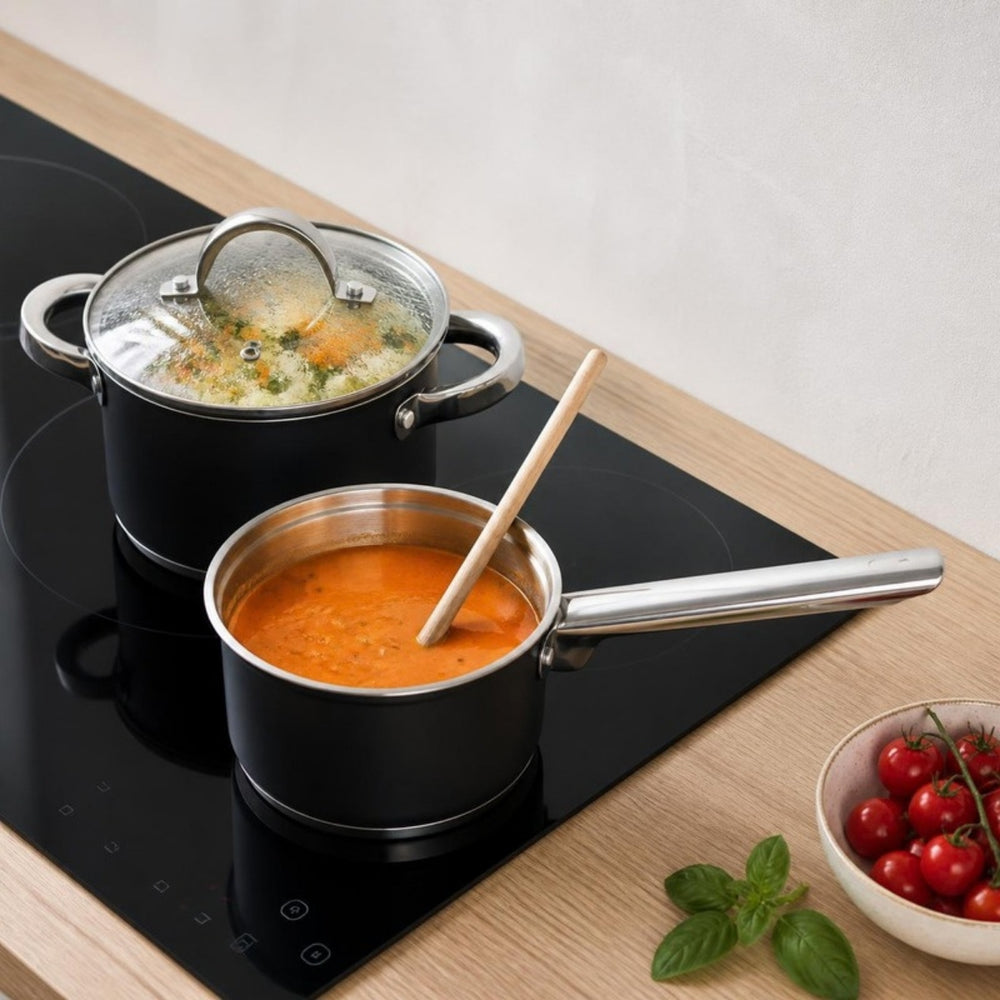Cooking zwarte kookpan met groentesoep en zwarte steelpan met tomatensoep op inductie