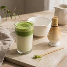 Matcha latte in een lange glas. Witte matchakom met matcha, bamboe garde op houder en matchalepel