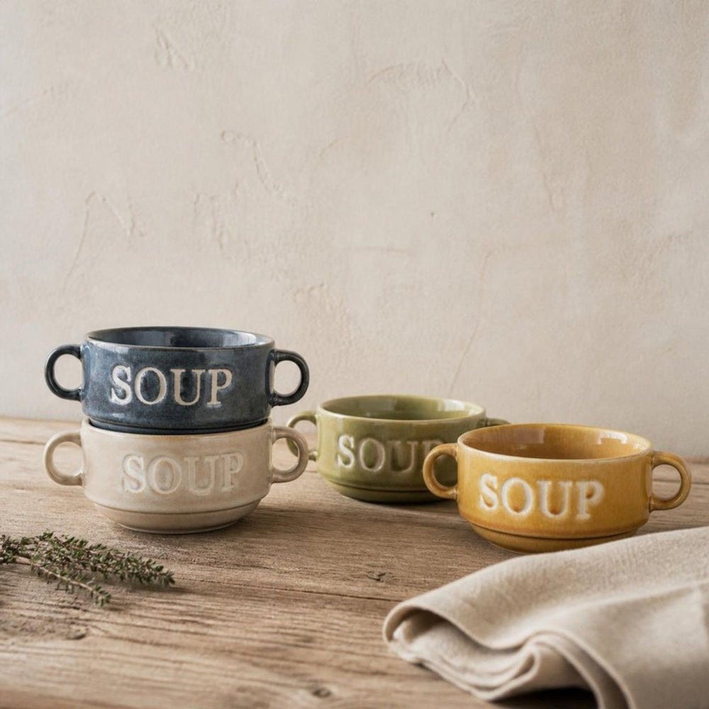 Vier Soup soepkommen in vier kleuren, deels gestapeld, op een eiken tafel